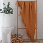 A wooden rack is creatively adorned with a mustard linen throw.