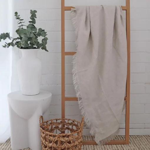 A natural linen throw gracefully hangs from a wooden rack.