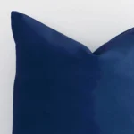 The corner of this outdoor square cushion cover is shown close up. The solid colour design and blue colour are shown in greater detail.