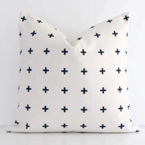 Colourful patterned cushion cover in front of a white wall. It has a square size and is made from a linen material.