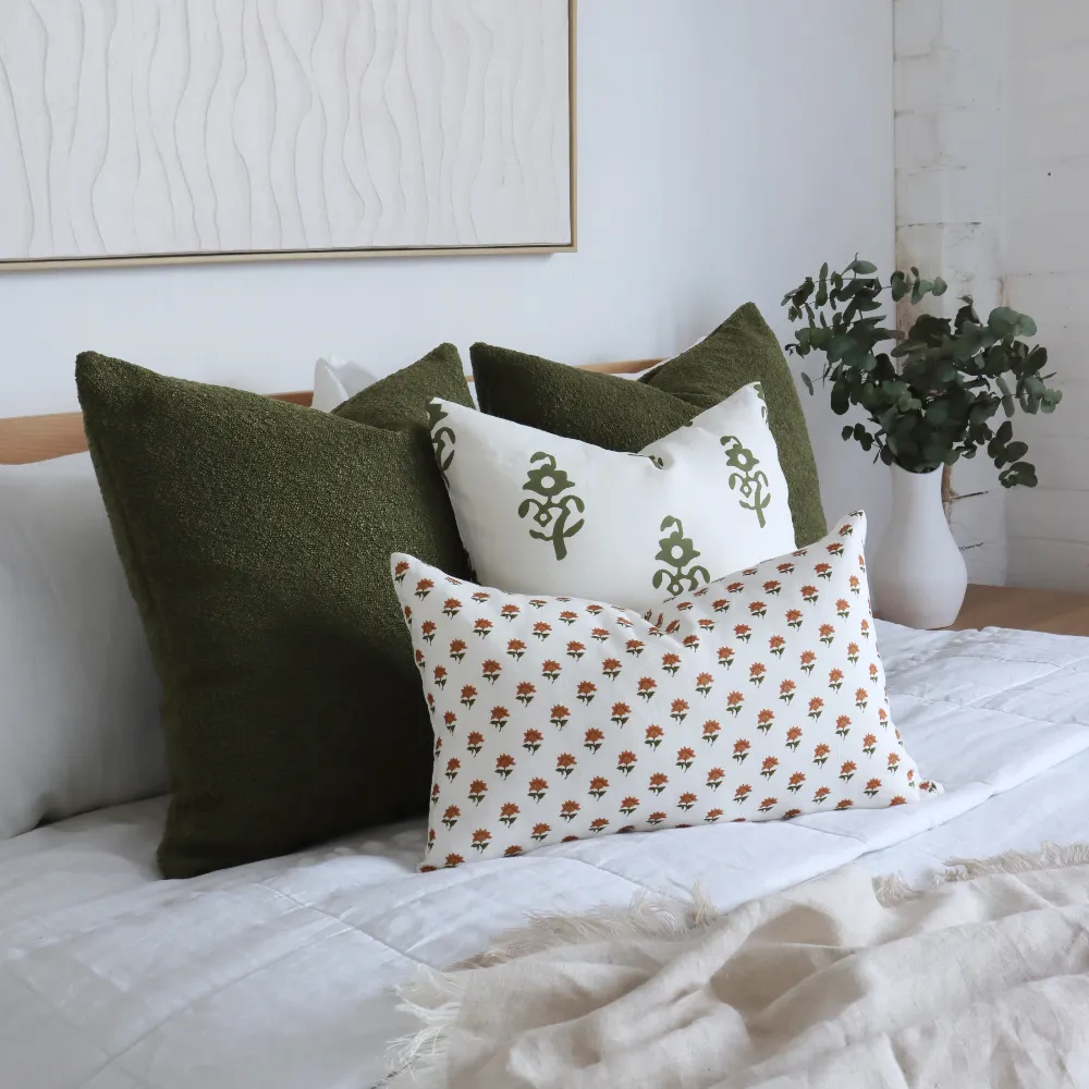 Arrangement of cushions on a bed. There are different sized cushion covers in the scene.