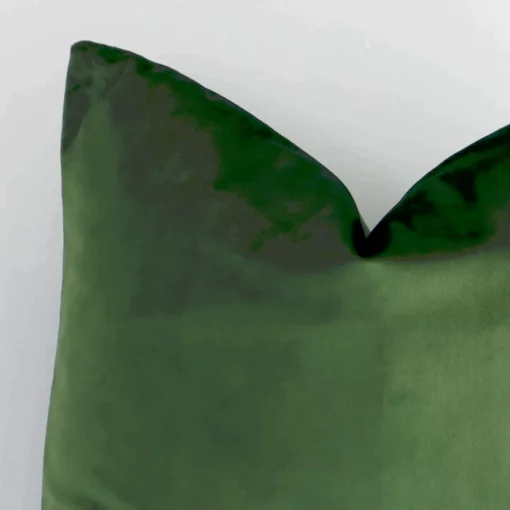 Cropped shot of top left corner of this solid colour forest green cushion cover. This viewpoint shows the velvet fabric and square shape with more precision.