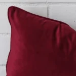 A zoomed view of this velvet maroon cushion’s corner in a rectangle size.