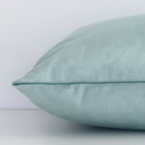 Side perspective showing seam of rectangular mint cushion cover that has a solid colour motif on its velvet fabric.