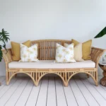 A set of 5 mustard outdoor cushions sits on a rattan seat nestled against a white wall.