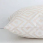 Side angle shot of outdoor square cushion cover. The beige geometric printed on it is shown along its seams.