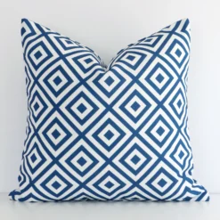 A pretty geometric outdoor cushion cover is shown against a white wall. It features a square shape and a blue colour finish.