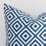 A close up shot showing the top left side of this square outdoor cushion cover. The blue tone and geometric design are magnified.