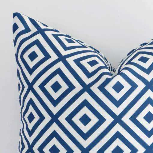 A close up shot showing the top left side of this square outdoor cushion cover. The blue tone and geometric design are magnified.