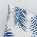 Enlarged shot of a rectangualr blue cushion cover that highlights that palm motif on its outdoor fabric.