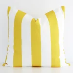 Yellow striped cushion cover in front of a white wall. It has a large size and is made from an outdoor material.