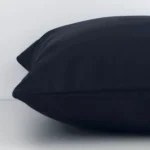 Side perspective showing seam of square black cushion cover that has a solid colour style on its outdoor fabric.