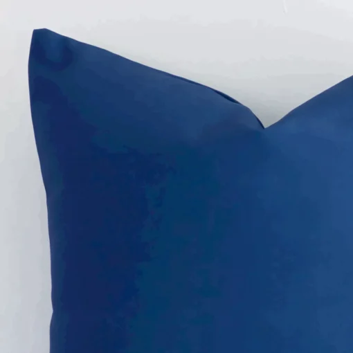 Close range image of blue solid-coloured cushion. The square size and material linen can be seen in detail.