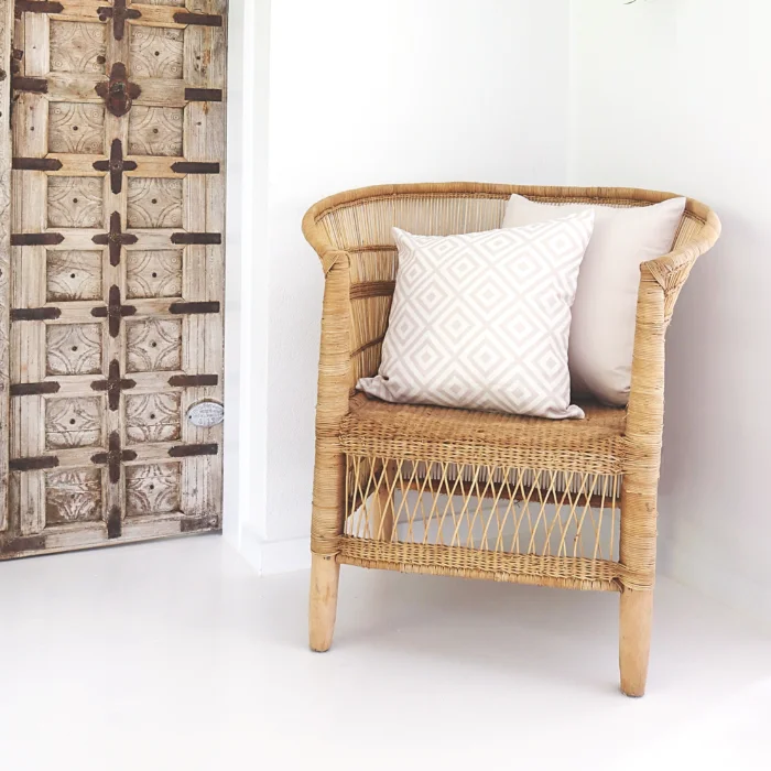 Beige outdoor cushions arranged on a wicker outdoor single chair