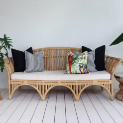 Five black outdoor cushions arranged on a rattan seat in a breezy lounge.