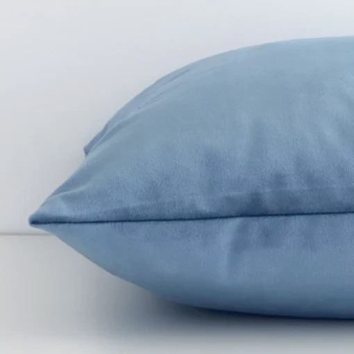 Enlarged image of the side of this stone blue velvet cushion. The angle highlights how the square design and solid colour finish are joined along the seam.