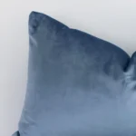 This image shows a stone blue solid-coloured cushion cover from a very close range. The rectangular size and velvet material are more clearly shown.